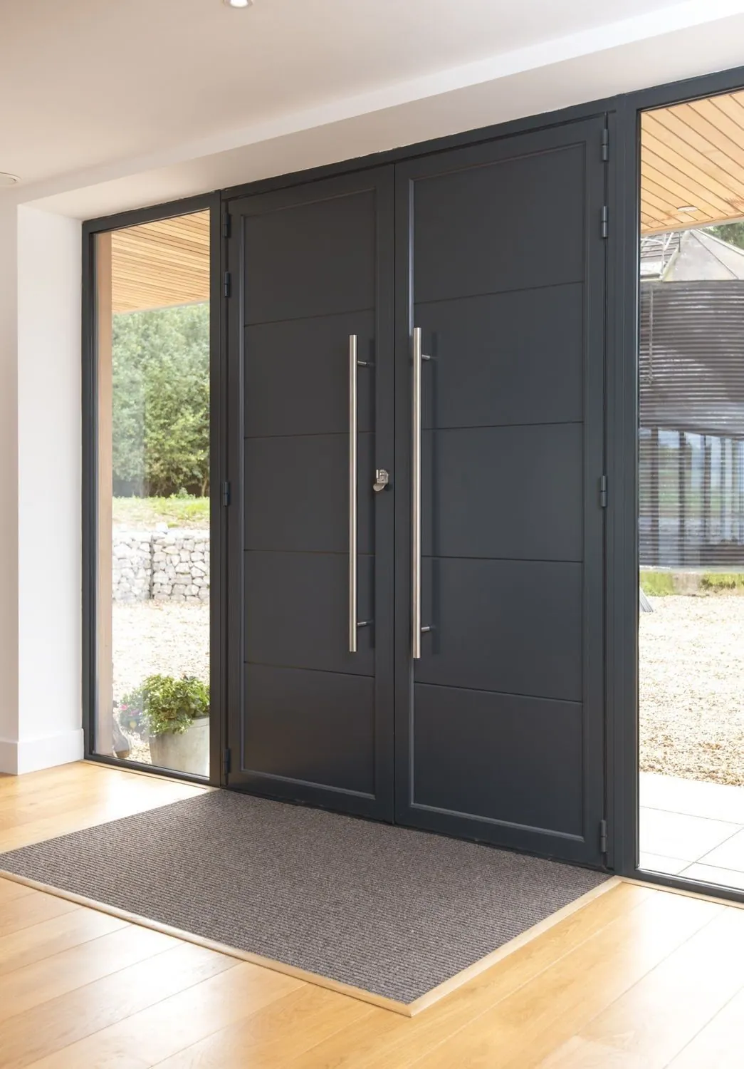 Brushed bronze aluminium pivot door with an illuminated LED handle at night