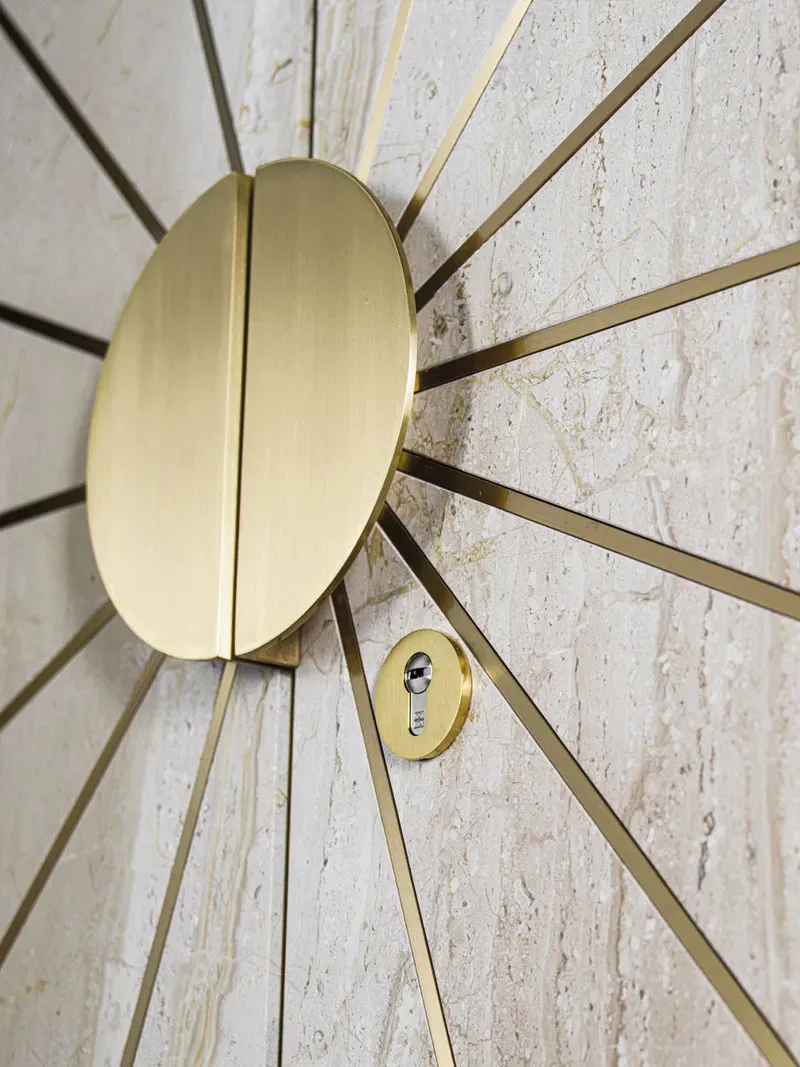 Marble door with brass sunburst rays and a half-moon handle