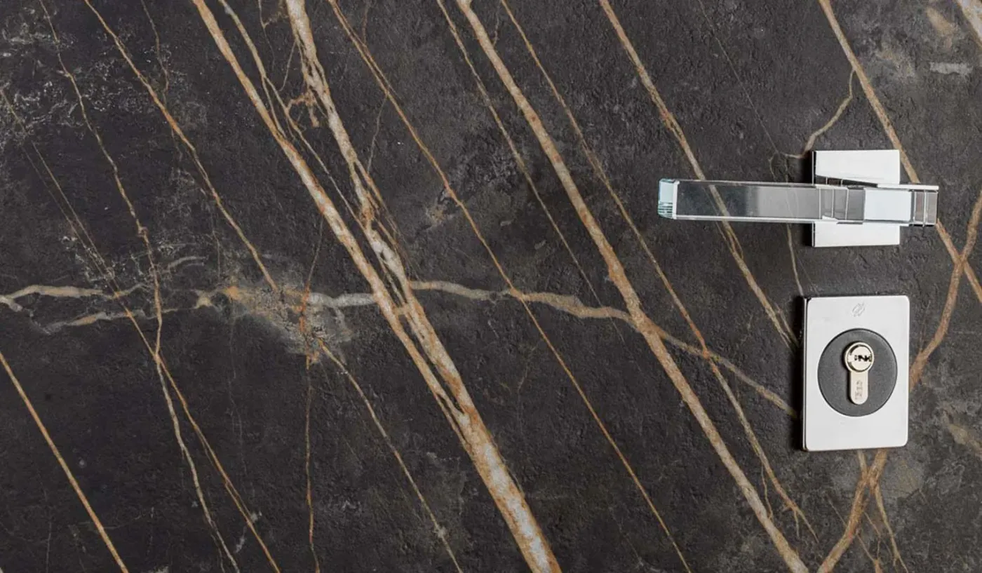 Black-and-gold marble-effect door face with a chrome lever handle and euro-cylinder lock