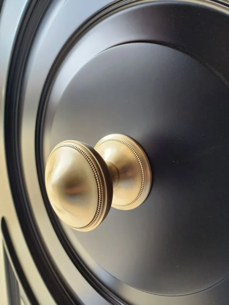Satin-brass beaded-edge centre knob on a black gloss circular moulded door panel