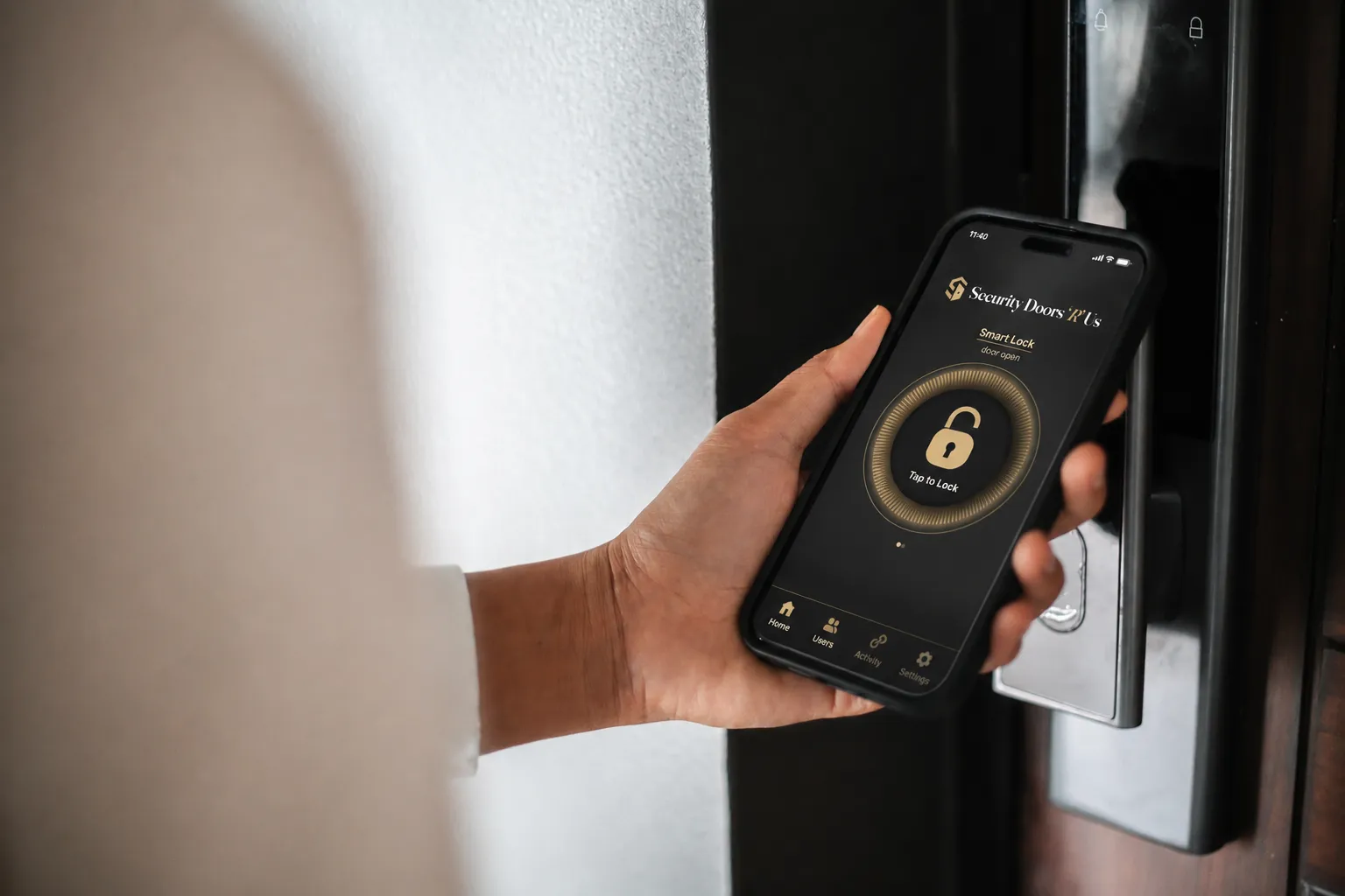 A hand holding a phone showing the Security Doors R Us smart-lock app beside a door