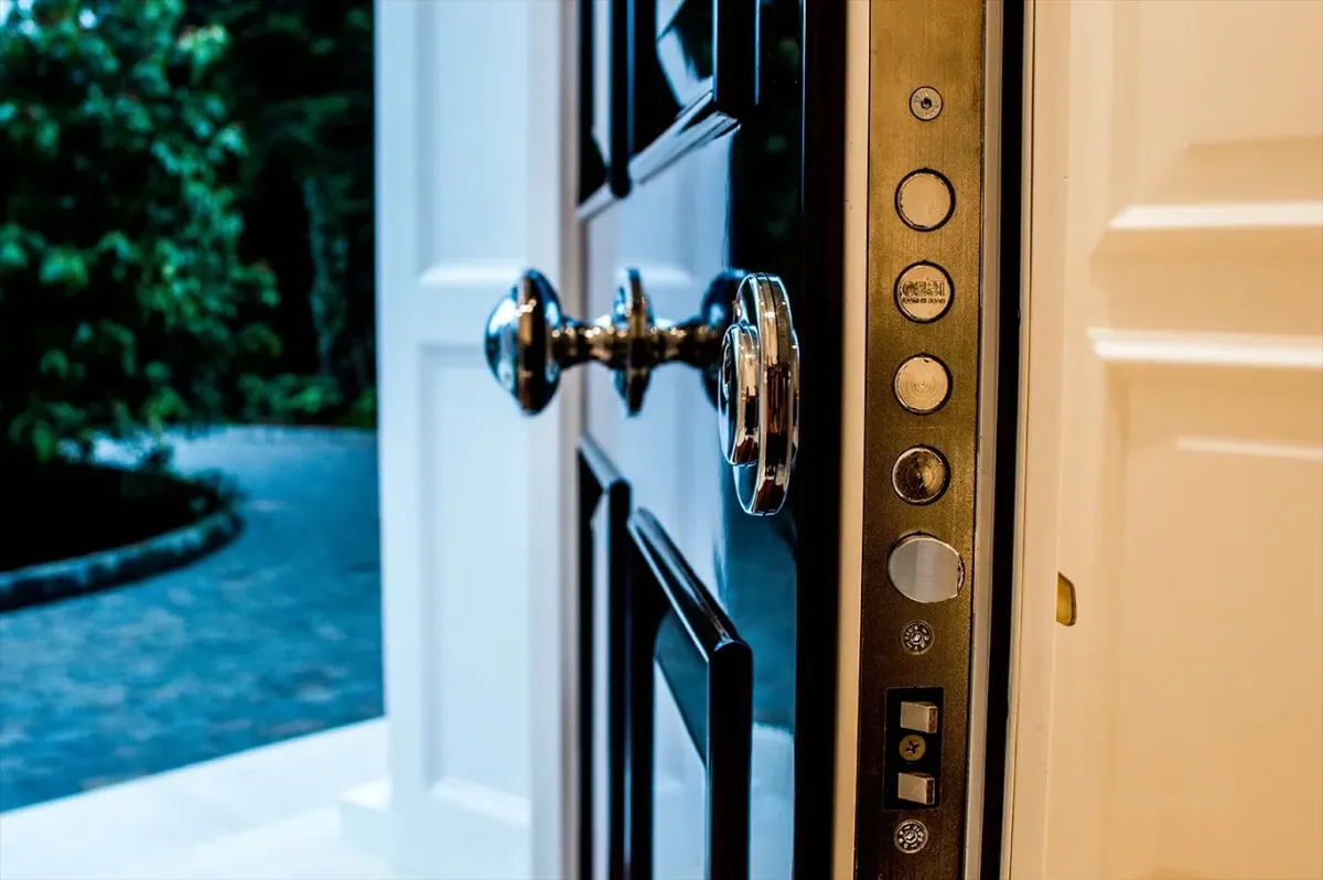 Black gloss security door open at dusk showing chrome multi-point locking bolts along the edge
