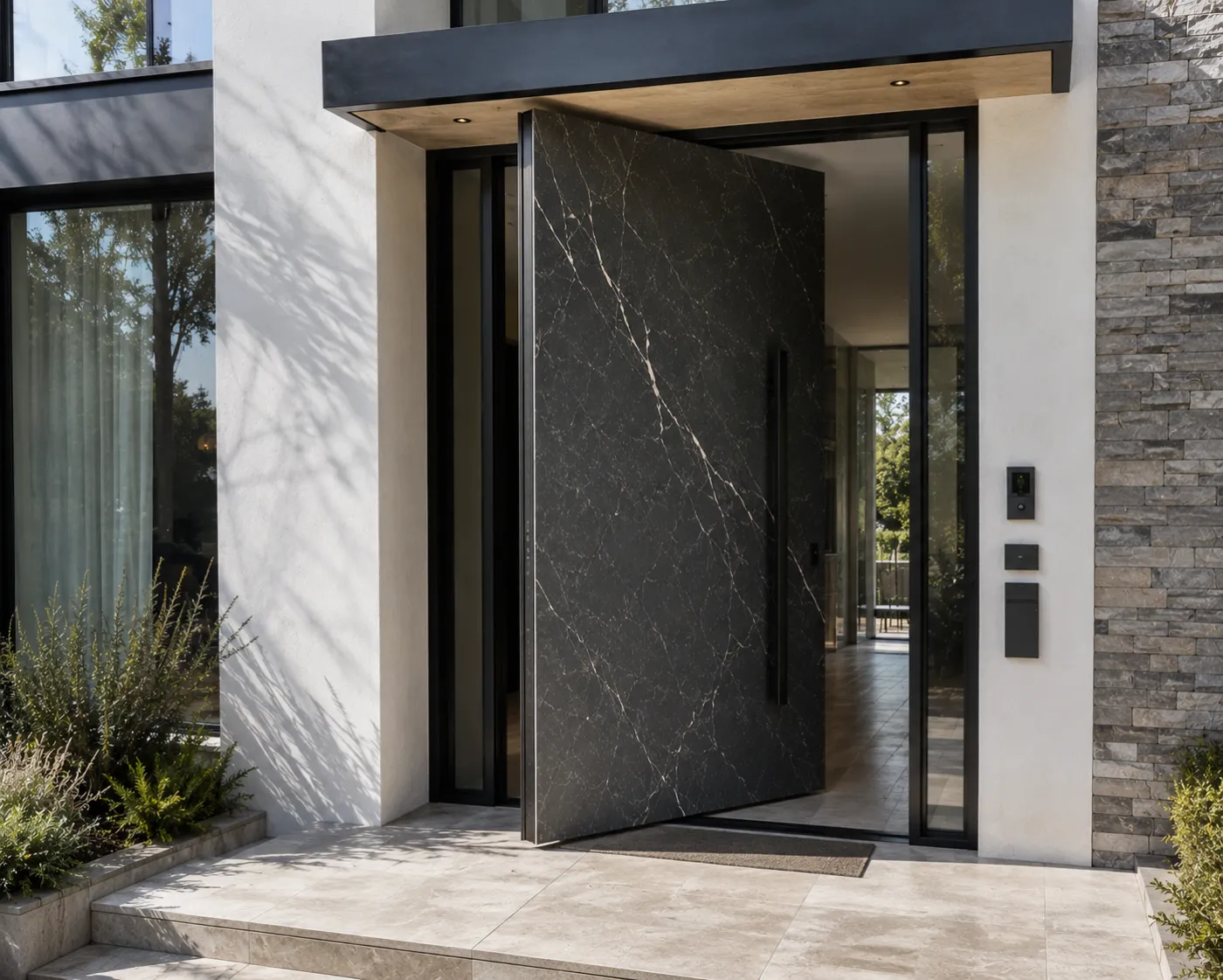 Dark veined-marble pivot door ajar in daylight with a keypad entry against a stacked-stone wall