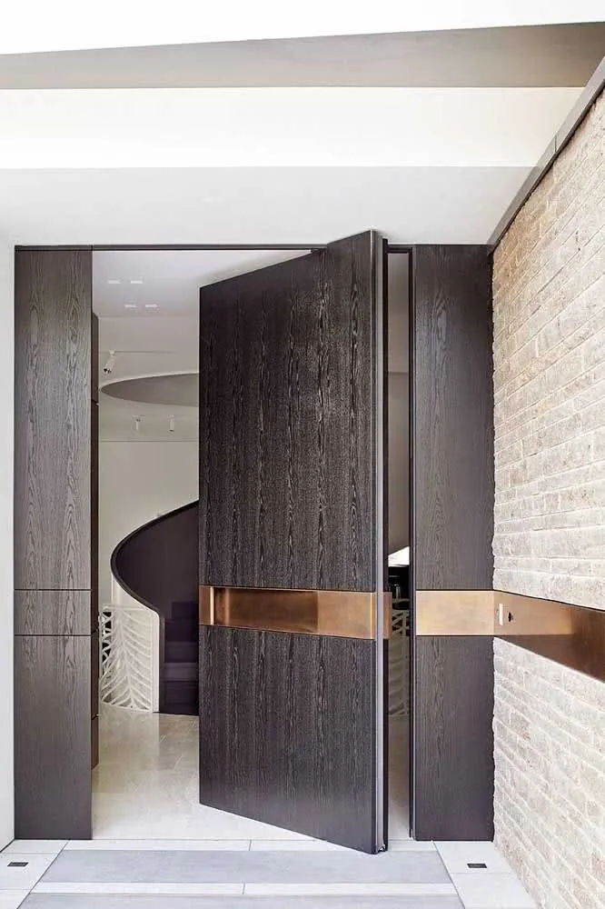 Dark-oak pivot front door with a horizontal copper inlay band