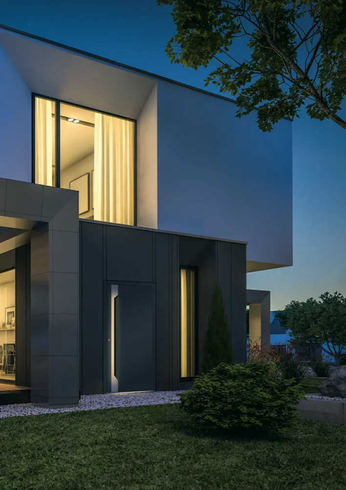 A premium aluminium front door at dusk, warm light glowing from inside the home