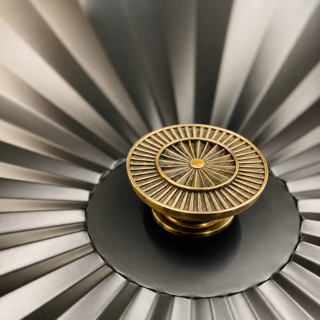 Antique-brass sunburst medallion door knob staged on a fluted metal fan
