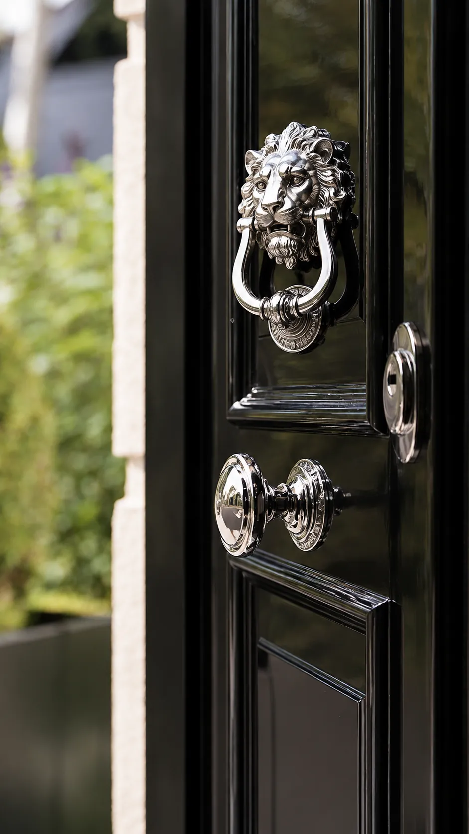 Polished nickel lion-head knocker, knob and key escutcheon on a black door