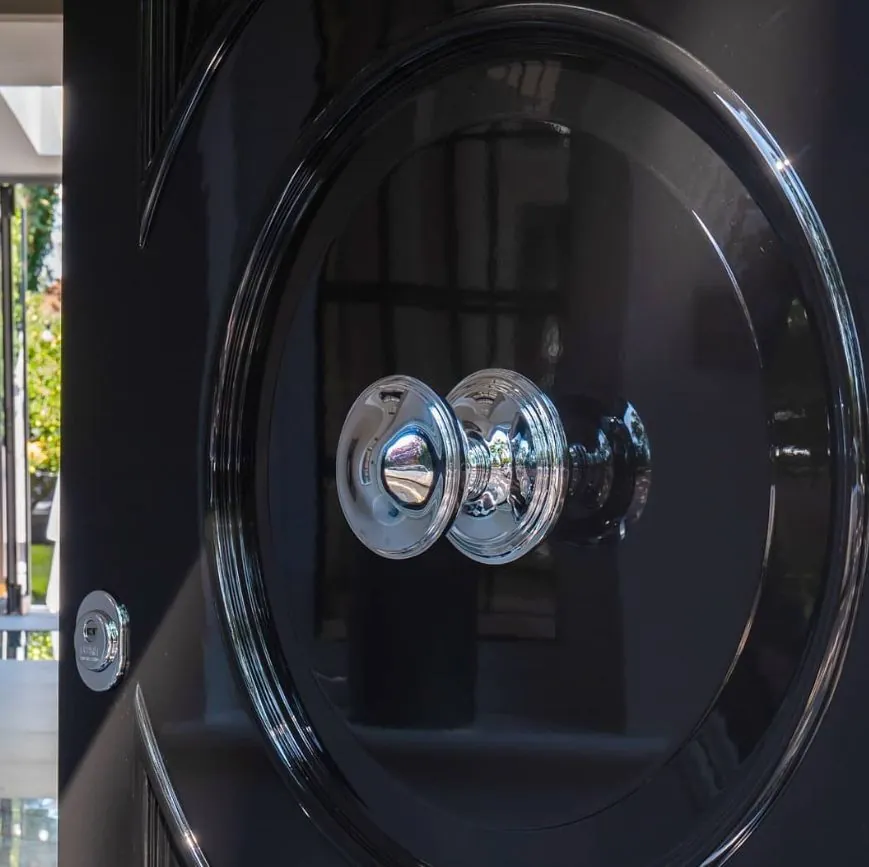 Polished chrome centre knob and key escutcheon on a gloss-black door panel